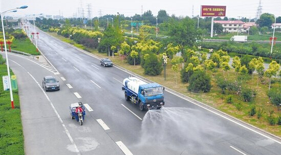 图为道路洒水车在机场连接线洒水抑制扬尘。